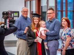 Female RN to BSN student at commencement with family.