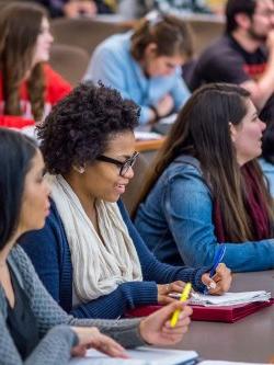 photo of students in class smiling and taking notes