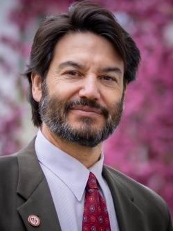 Montclair State University President Jonathan Koppell poses by a blooming tree on campus.