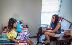 Two students hanging out in a dorm room in Machuga Heights.